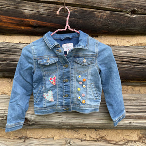 Denim jacket with colorful patches on a wooden background