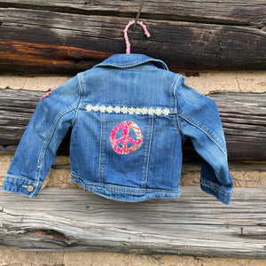 Blue denim jacket with peace sign design on a wooden surface