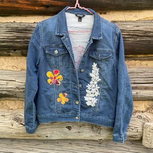 Blue denim jacket with floral embroidery on a wooden background