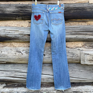 Back of jeans with a red velvet heart on the left pocket and embroidered flowers on the upper right waistband.