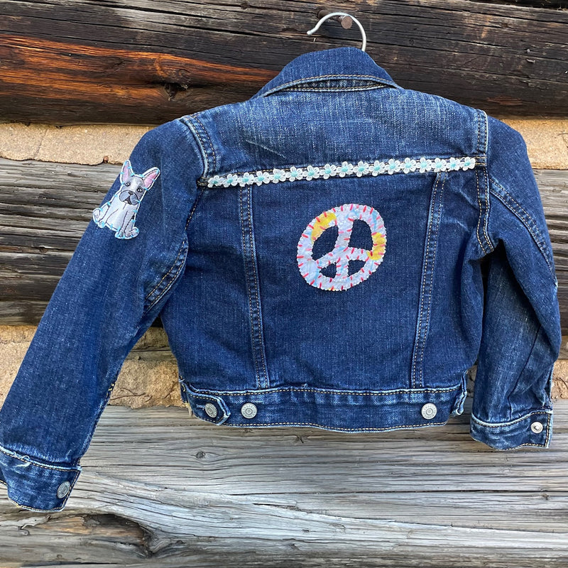 Back of jean jacket with peace sign patch and dog patch on shoulder.