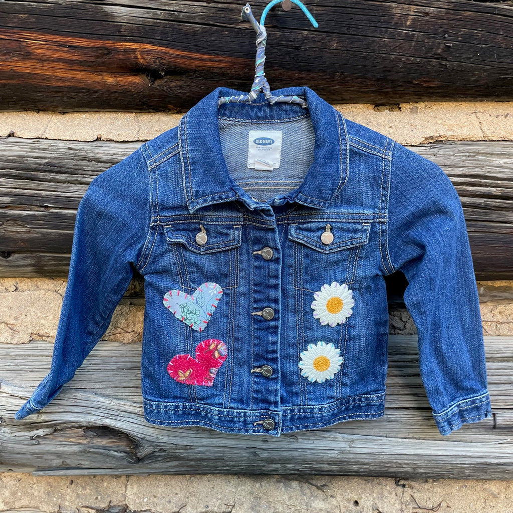 Front of jean jacket with flower and heart patches.