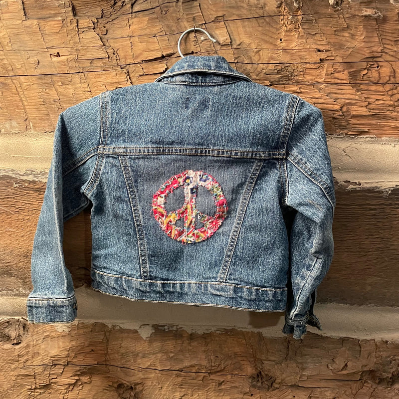 Blue denim jacket with a floral peace symbol patch