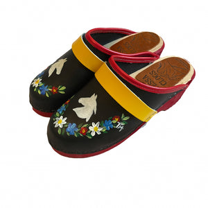 Pair of black clogs with floral designs and colorful straps on a white background