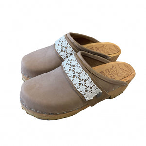 A pair of taupe leather clogs with white floral lace straps, shown on a plain white background.