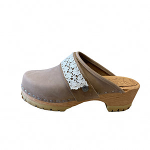 A taupe leather clog shoe with a light brown wooden heel and sole, featuring a white crocheted lace detail across the top strap.