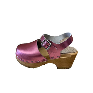 A metallic pink leather clog sandal with a wooden  heel and a silver buckle, shown from a side profile on a white background.