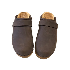 A pair of dark brown leather clogs with  straps and light tan soles, shown against a plain white background.