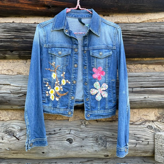 Front of jean jacket with flower patches on left and right sides.