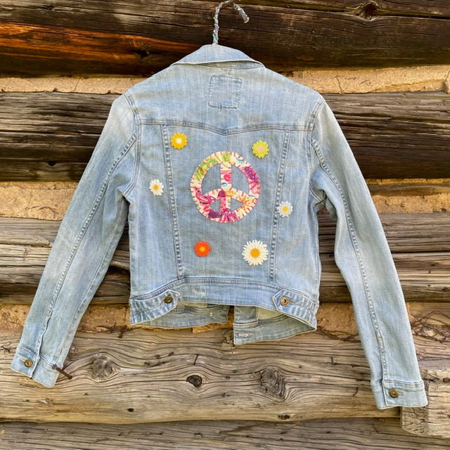 Back of jean jacket with Large peace sign surrounded by small daisies.