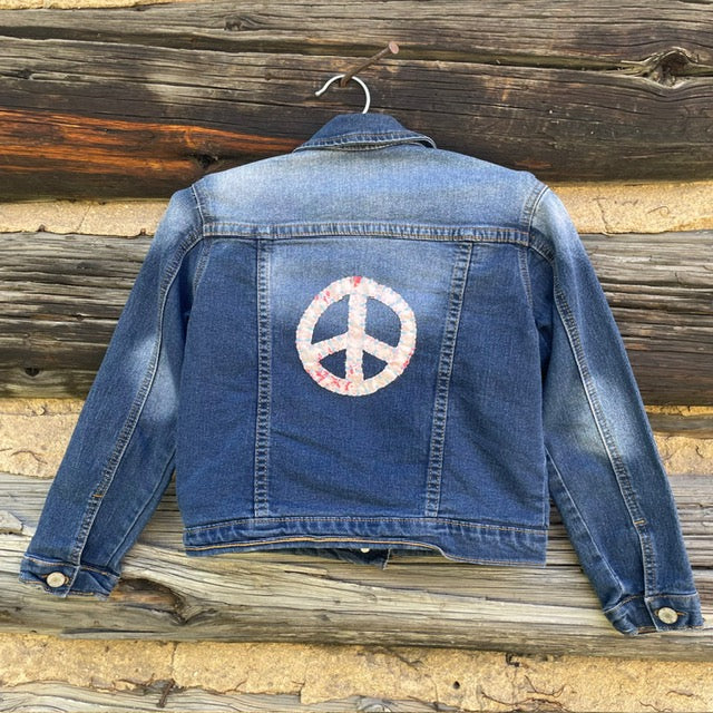 Back of jean jacket with large pale pink peace sign