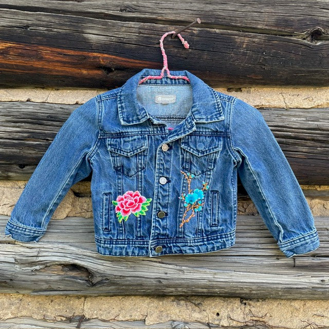 Front of jean jacket with two flower patches sewn on.