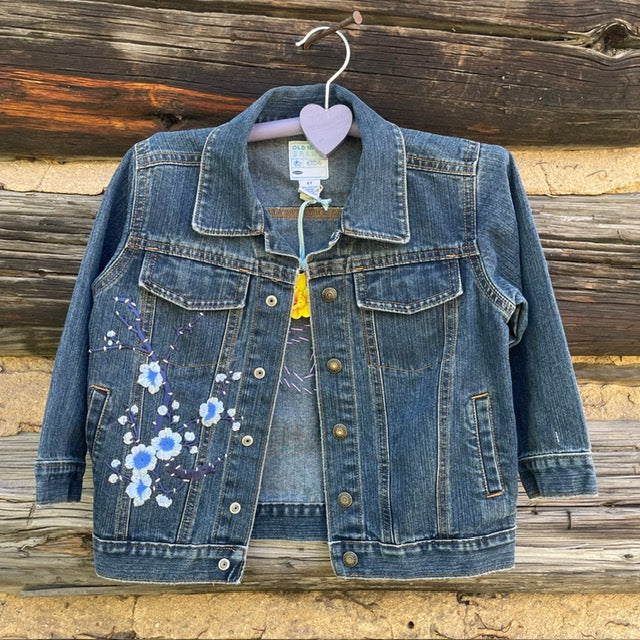 Front of jean jacket with blue flower patch.