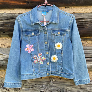 Front of jean jacket with four flower patches sewn on.