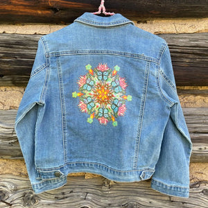 Back of jean jacket with printed mandala decal in center.