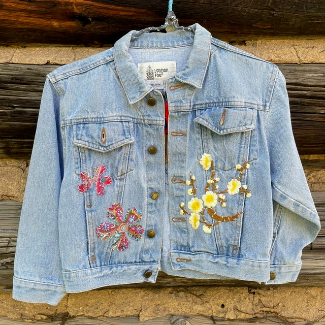 Front of kids jean jacket with three flower patches sewn on front panels.