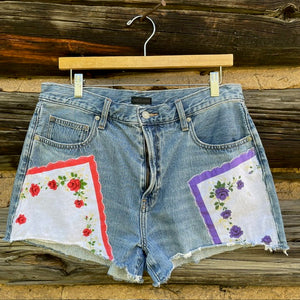 Front of jean shorts with a red rose napkin patch and a purple rose napkin patch.