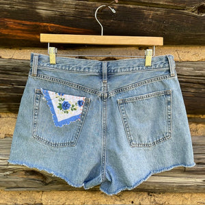 Back of jean shorts with blue rose napkin patch.