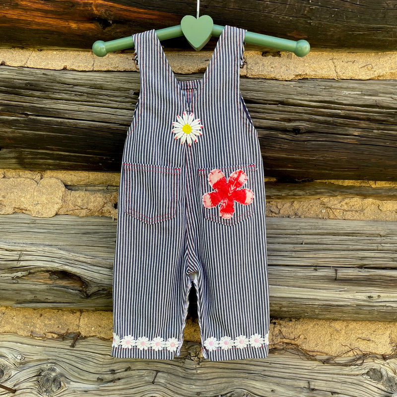 Striped overalls with a daisy cuff, white daisy patch, and pink flower patch.