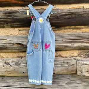 Back of overalls with daisy cuff, and a heart, daisy, and butterfly patch.