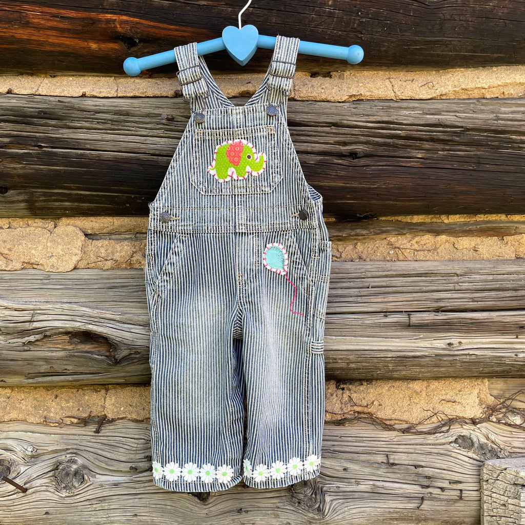 Front of striped overalls with green elephant patch, blue balloon patch, and a daisy cuff.