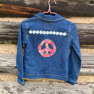 Blue denim jacket with floral peace symbol and white flowers on a wooden background
