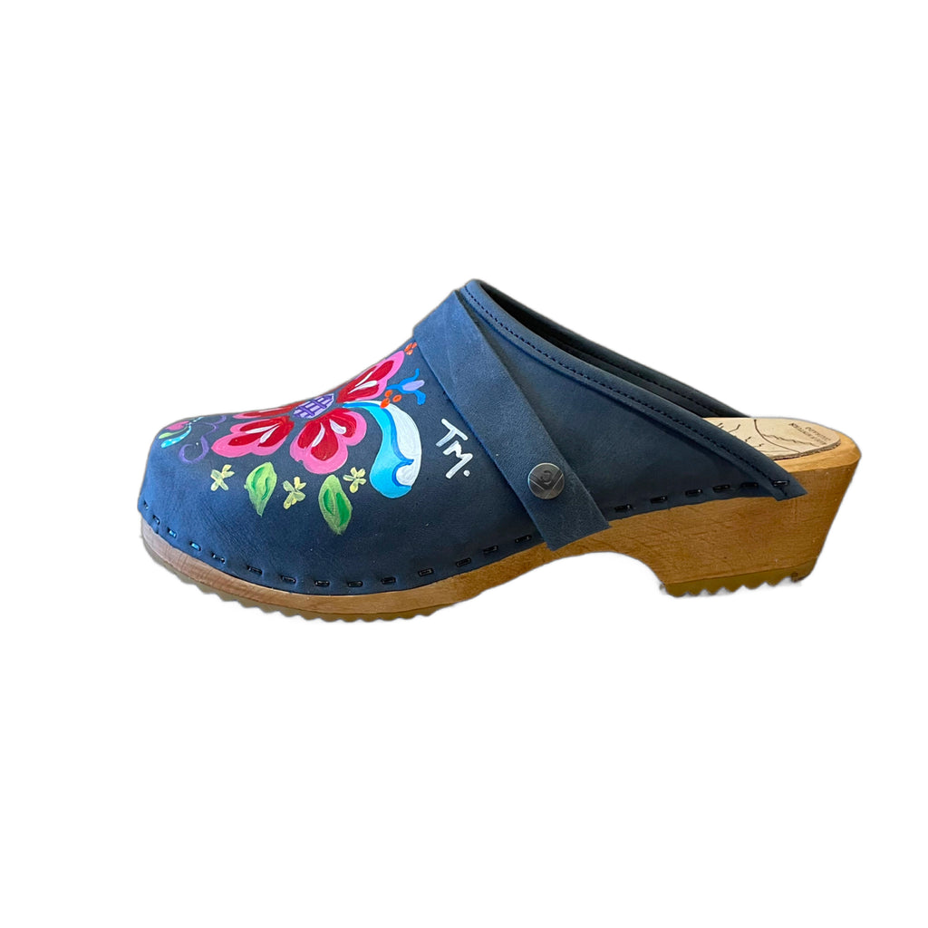 Traditional heel Tessa clog in denim blue leather and natural wood stained soles with the hand painted Petra design and a plain denim blue snap strap.