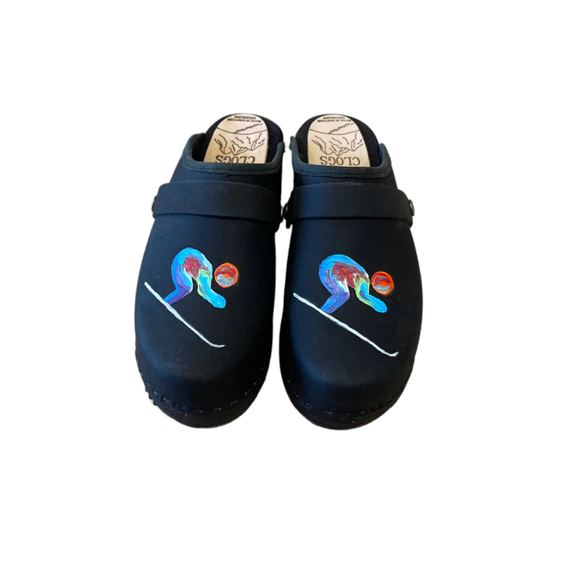 Traditional heel clog in black leather and black stained soles, with our special edition world championship hand painted design on each shoe. Shown with a black snap strap.