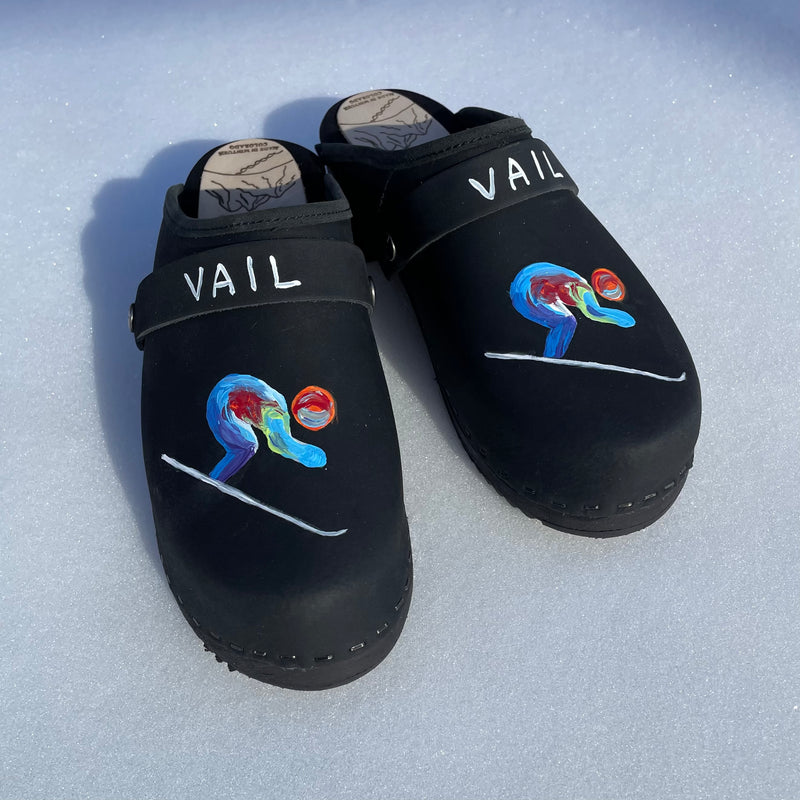 Traditional heel clog in black leather and black stained soles, with our special edition world championship hand painted design on each shoe. Shown in the snow with a black VAIL painted snap strap.