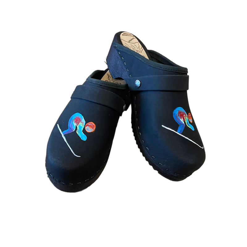 Traditional heel clog in black leather and black stained soles, with our special edition world championship hand painted design on each shoe. Shown with a black snap strap.