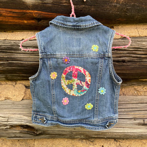 Denim vest with peace symbol and flowers on a wooden background