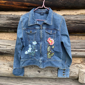 Blue denim jacket with floral embroidery on a wooden background