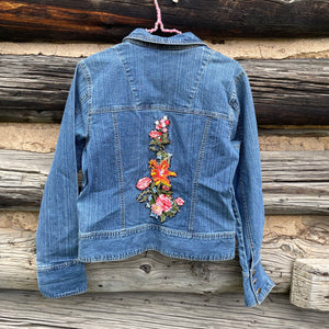 Blue denim jacket with floral embroidery on a wooden background