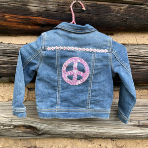 Denim jacket with a peace symbol design on a wooden background