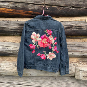 Denim jacket with floral embroidery on a wooden background