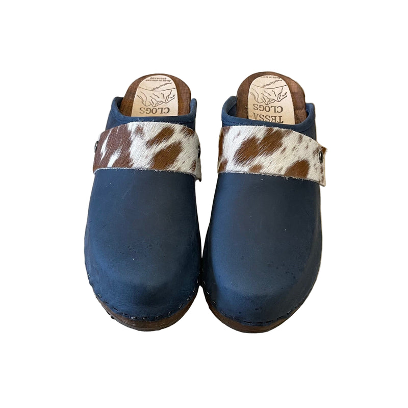Pair of blue clogs with cowhide straps on a white surface