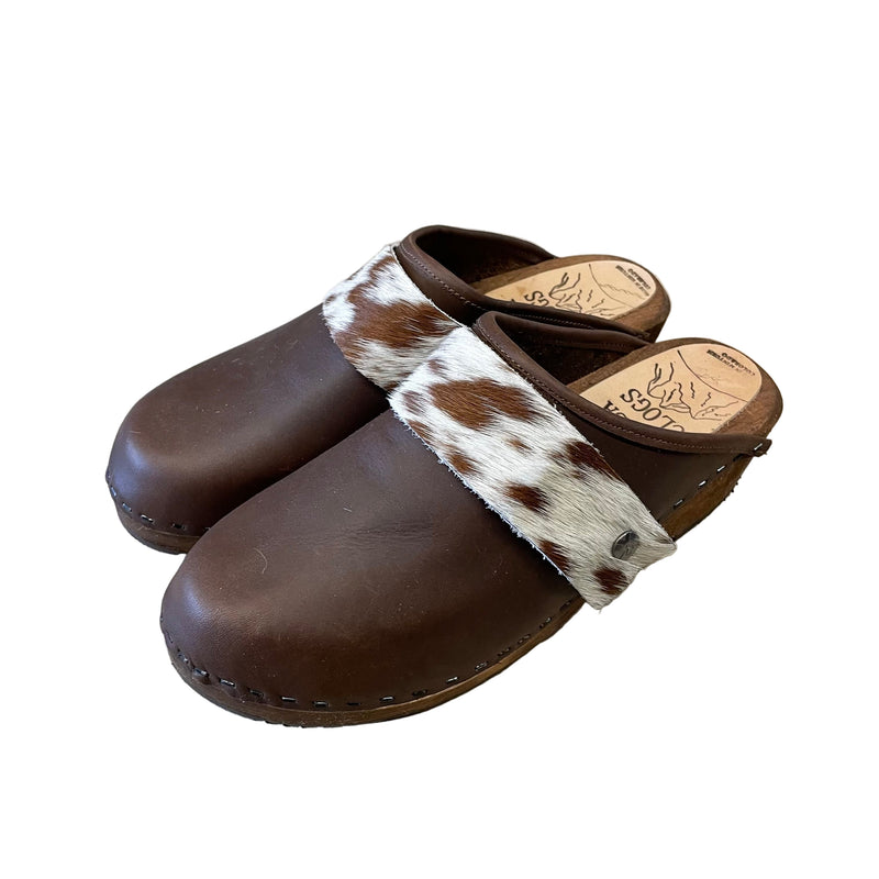 Brown leather clogs with cowhide pattern straps on a white surface