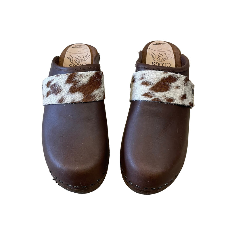 Pair of brown clogs with cowhide strap on a white background