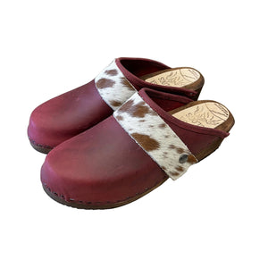 Maroon clogs with a cowhide strap on a white surface