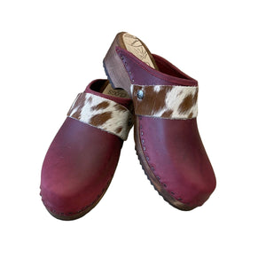 Pair of maroon clogs with cowhide straps on a white background