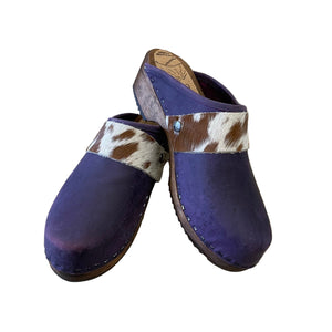 Pair of purple clogs with cowhide straps on a white surface