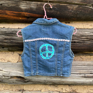 Denim vest with peace symbol design on a wooden background