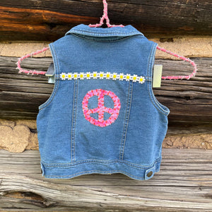 Blue denim vest with peace symbol and flowers on a wooden background