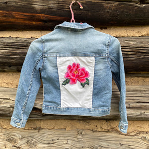 Denim jacket with a floral patch on a wooden background
