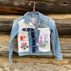Denim jacket with floral embroidery on a wooden background