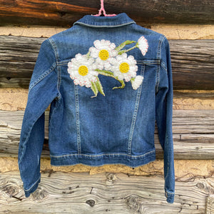 Blue denim jacket with floral embroidery on a wooden background